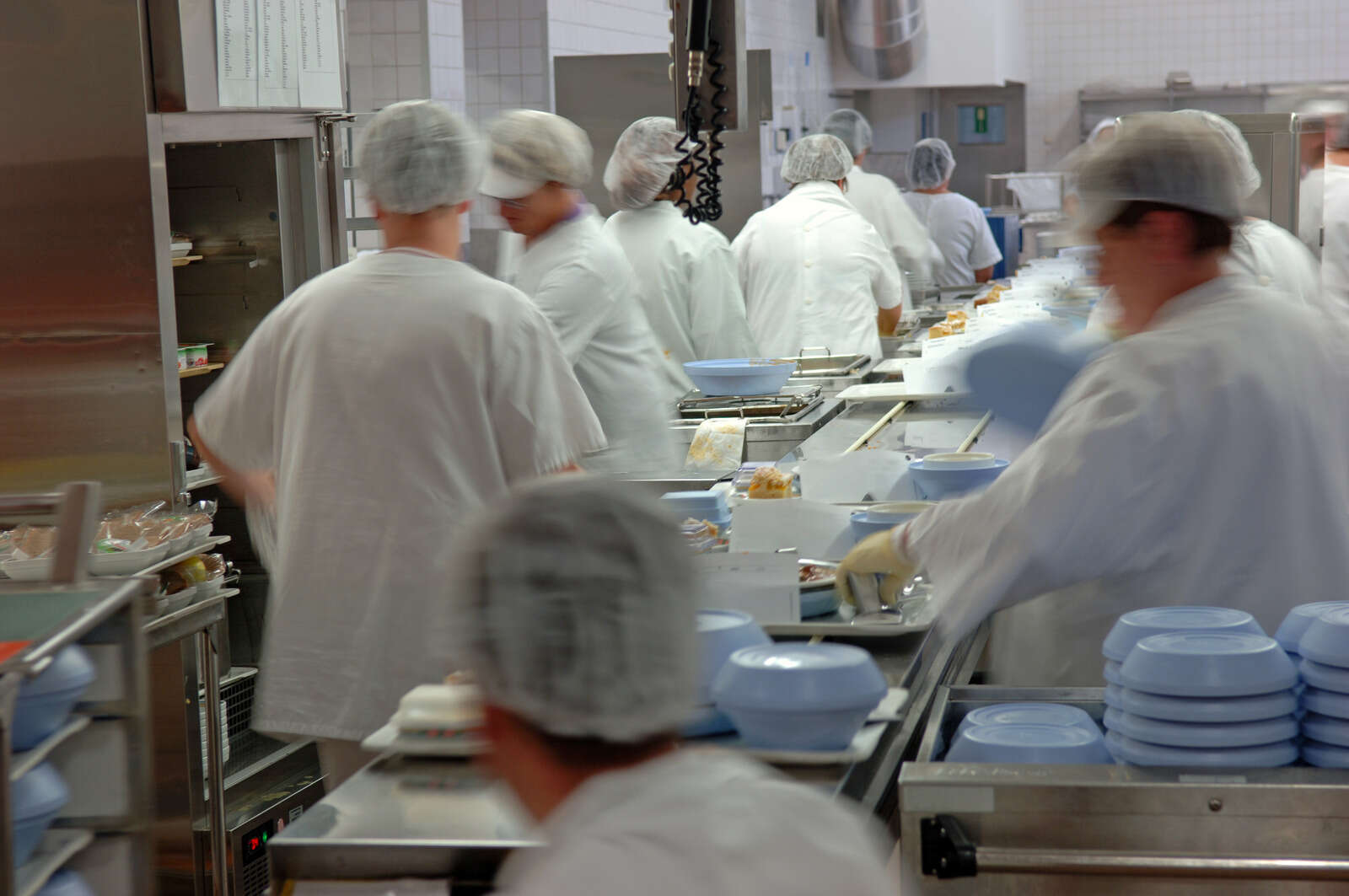 Cooks working in kitchen using stainless bench